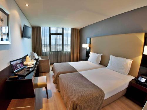 里斯本图里姆阿拉米达酒店的酒店客房配有一张床、一张书桌和一台笔记本电脑