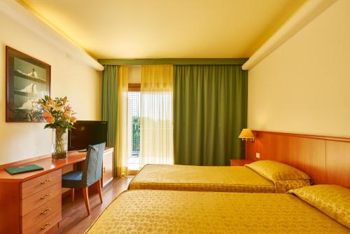 格拉多里亚托酒店的酒店客房配有一张床、一张书桌和一台电视。