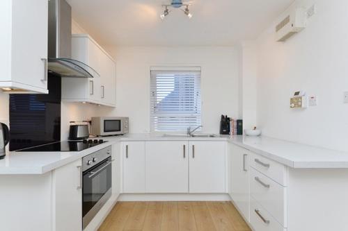 爱丁堡爱丁堡海滨公寓的白色的厨房配有白色橱柜和水槽