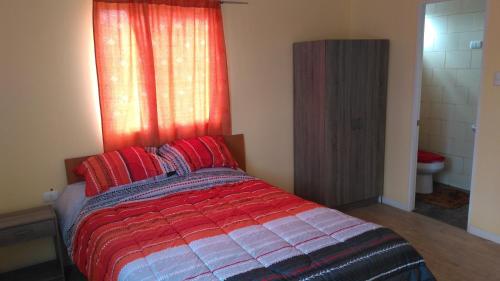伊基克Iquique sun的一间卧室配有一张带红色枕头的床和一扇窗户