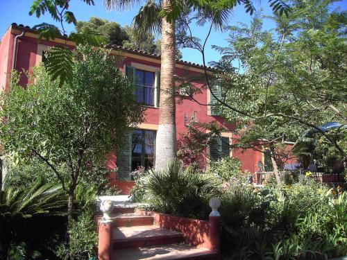 芒通橄榄树下酒店的前面有棕榈树的红色房子