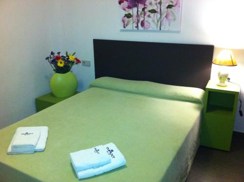 奥里韦拉海滩迪曼特蓝色公寓式酒店的一间卧室配有一张带毛巾和花瓶的床