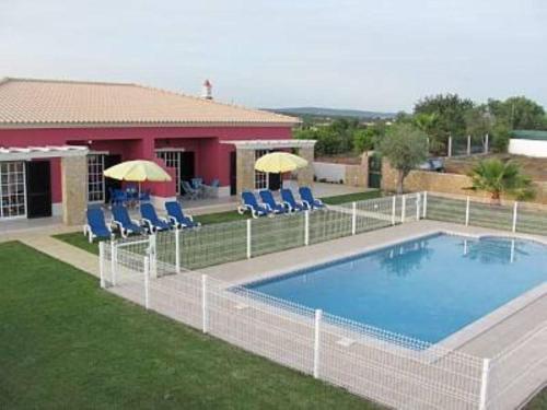 阿尔戈什梅萨维拉酒店的房屋旁的游泳池配有椅子和遮阳伞