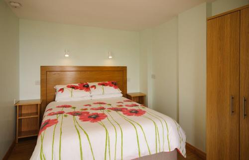 伦维尔Seabreeze Junior Suite Renvyle的一间卧室,床上有红色的鲜花