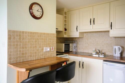 伦维尔Seabreeze Junior Suite Renvyle的厨房配有白色橱柜和墙上的时钟