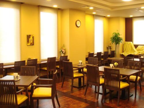 诹访市诹访英特2酒店的餐厅设有桌椅和墙上的时钟