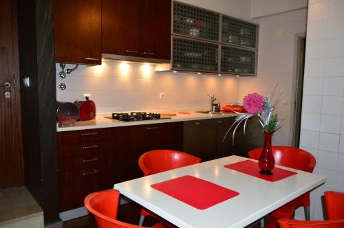 丰沙尔vista dos arrifes的厨房配有红色的椅子和一张带花瓶的桌子