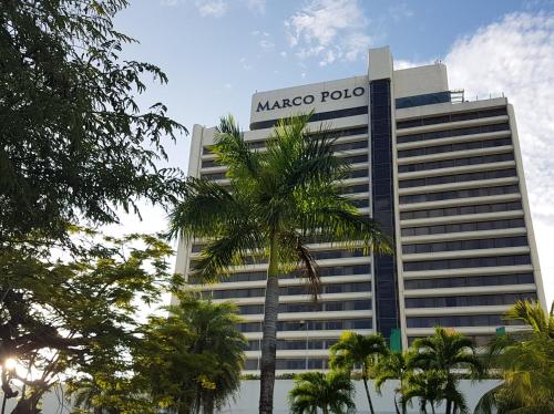 宿务Marco Polo Plaza Cebu的前方有棕榈树的马斯科马球建筑