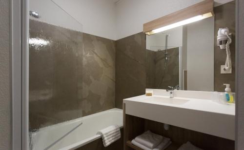Saint-PalaisHôtel-Restaurant de La Paix的浴室配有水槽、淋浴和浴缸。