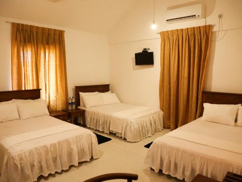 帕西库达Pasikudah Eco Village Hotel的酒店客房设有两张床和电视。