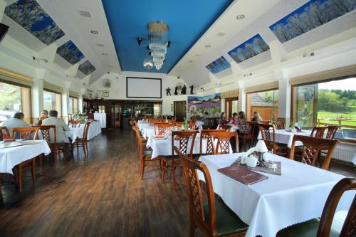 兹姆巴克Osada Koszałkowo Wieżyca的餐厅设有白色的桌椅,而客人则坐在桌子旁