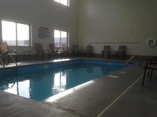 FairburyThe Edgewood Hotel and Suites的一座空的游泳池,里面摆放着椅子