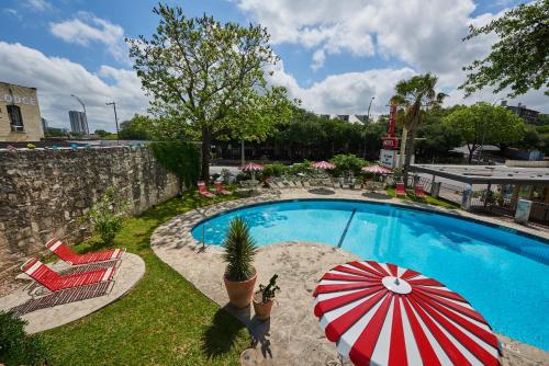奥斯汀Austin Motel的一个带红色和白色遮阳伞及椅子的游泳池