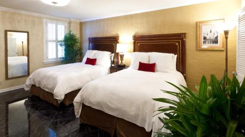 新奥尔良马萨林酒店的一间卧室配有两张带白色床单和红色枕头的床。