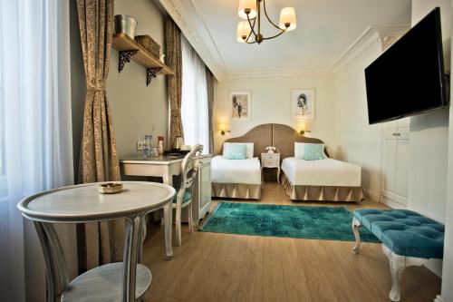 伊斯坦布尔Villa Blanche Hotel SPA & Garden Pool的酒店客房设有两张床和一张桌子。
