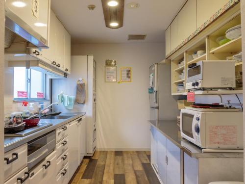 广岛广岛悦动酒店的厨房配有白色橱柜和冰箱。