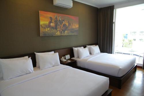 巴图萨马拉度假酒店的酒店客房设有两张床,墙上挂有绘画作品