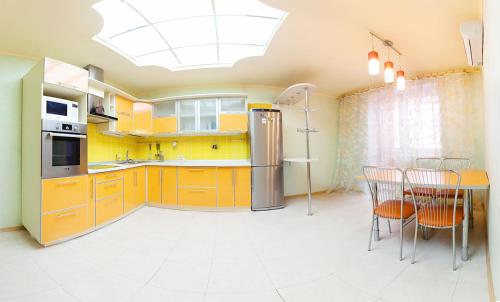 鄂木斯克Omsk Sutki Apartments on 70 let oktyabrya 16/4的厨房配有黄色橱柜和桌椅