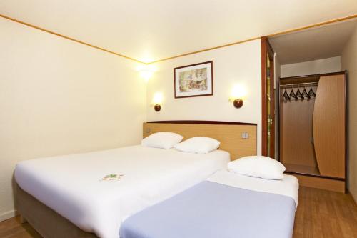 绍莱钟楼索雷酒店的配有白色床单的酒店客房内的两张床