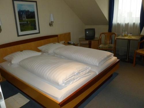 慕尼黑尤沃斯塔特翰森酒店的一张配有白色床单和枕头的大床