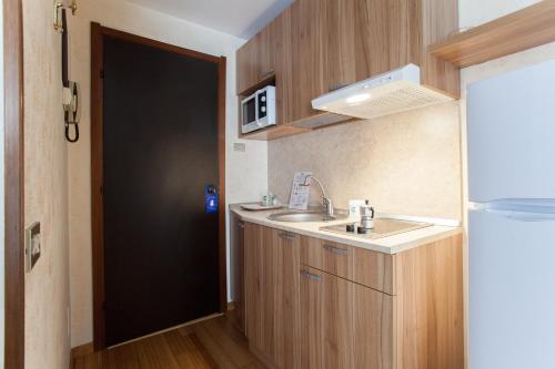 米兰德赛莎诺住宅酒店的一个带水槽和黑色门的小厨房