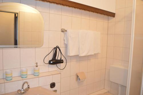 巴特卡尔斯哈芬Hotel Zur Rose的白色瓷砖浴室设有水槽和镜子