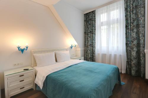 卡罗维发利Ferdinandhof Apart-Hotel的一间卧室配有一张带蓝色毯子的床和窗户。