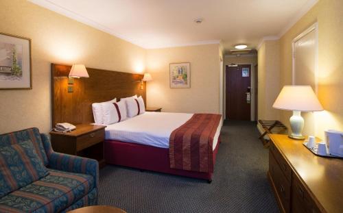 考文垂考文垂南柑橘可母帕斯酒店 的配有一张床和一把椅子的酒店客房