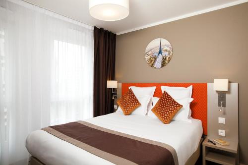 巴黎巴黎罗莎帕克斯公寓式酒店的一间卧室配有一张带橙色床头板的大床