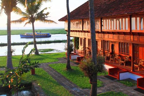 库玛拉孔Coconut Lagoon Kumarakom- CGH Earth的一座在水中和棕榈树上划船的建筑