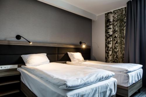 Koło马苏里克酒店的配有白色床单的酒店客房内的两张床