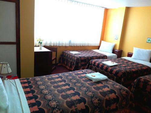 普诺Ayma Hostel Puno的酒店客房设有两张床和窗户。