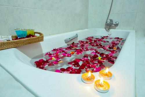 彬乌伦Thiha Bala Hotel的装满红花和蜡烛的浴缸