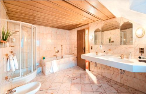 索梅拉伽斯特苏微本拉姆酒店的浴室配有2个盥洗盆、浴缸和淋浴。