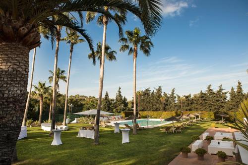 索托格兰德Hotel Encinar de Sotogrande的一个带游泳池和棕榈树的度假村