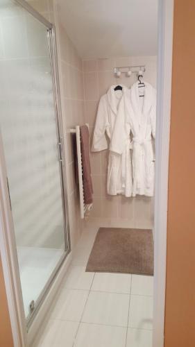 VénérandClos des Morillons的带淋浴和白色浴袍的浴室。