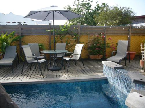 西班牙港Trinidad Gingerbread House的游泳池旁配有桌椅和遮阳伞