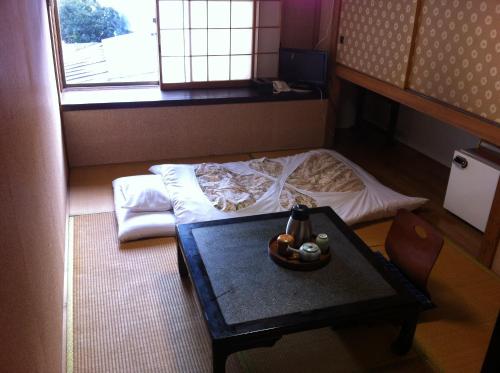 千曲市卡梅西日式旅馆的小房间设有床、桌子和窗户