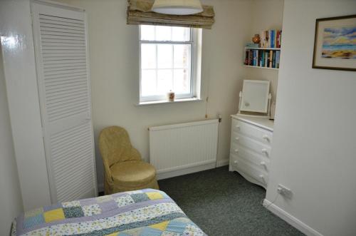 托特尼斯The Little Elbow Room的一间卧室配有一张床、一个梳妆台和一扇窗户。