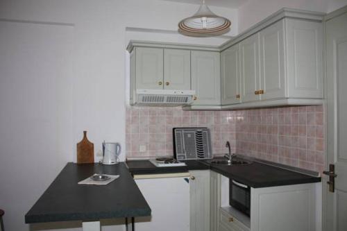 卡西奥皮Philippos Kassiopi Apartments的厨房配有白色橱柜和黑色台面