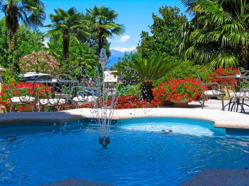坎诺比奥Hotel Villa Delle Palme的花卉花园中游泳池中的喷泉