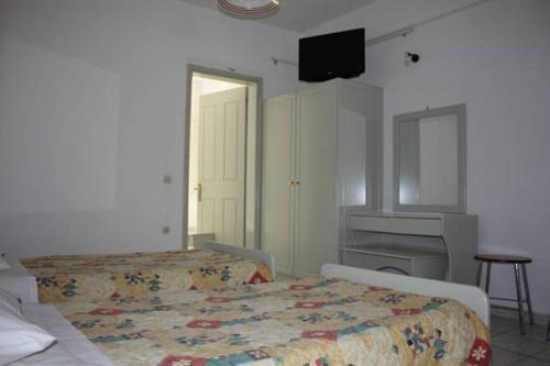 卡西奥皮Philippos Kassiopi Apartments的一间卧室配有两张床、一张桌子和一台电视。