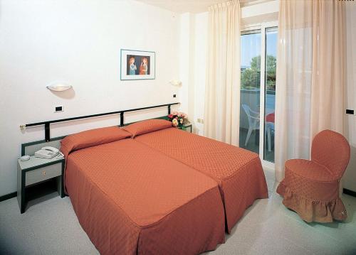 卡托利卡Residence Hotel Club House的一间带一张床和一把椅子的卧室以及一个阳台