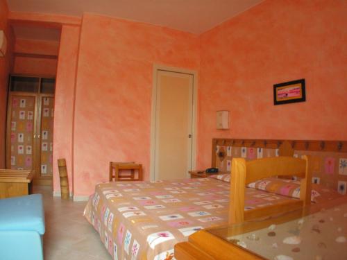 圣多米诺莱万特酒店的一间设有床铺的卧室,位于一个拥有橙色墙壁的房间
