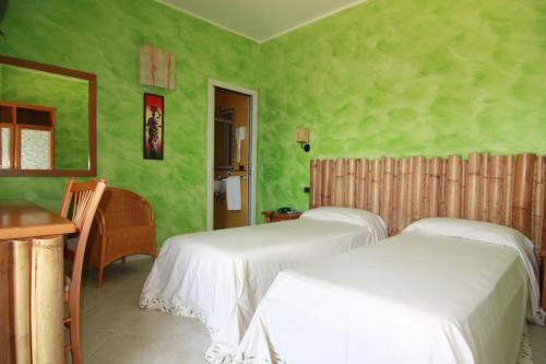 圣多米诺莱万特酒店的绿墙客房内的两张床