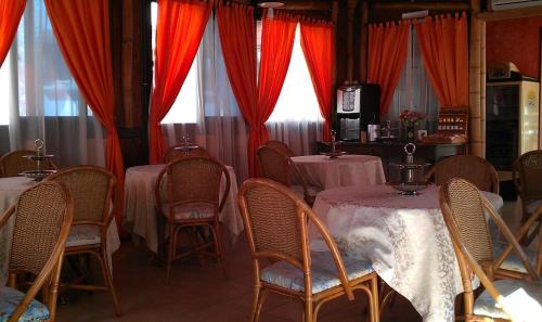 圣多米诺莱万特酒店的一间配备有桌椅和红色窗帘的用餐室