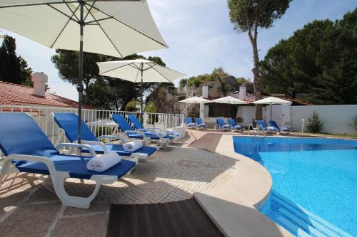 塞辛布拉Villa Branca do Castelo的游泳池旁的游泳池配有蓝色椅子和遮阳伞