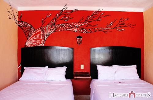 梅里达Hotel Hacienda Cortes的红色墙壁的客房内的两张床