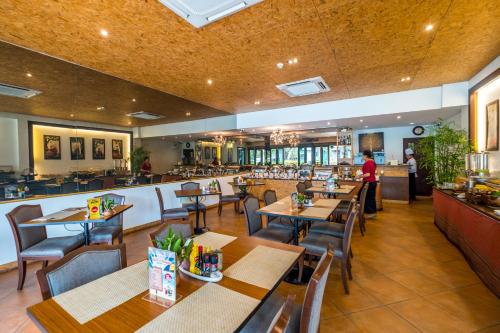 清莱清莱乐帕塔酒店 SHA Extra Plus的一间带木桌椅的餐厅和一间酒吧