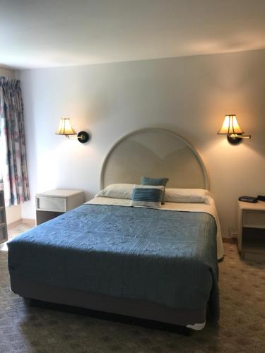 五月岬郡Cape Harbor Motor Inn的一间卧室配有一张大床和两盏灯
